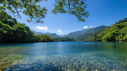 A beautiful lake surrounded by trees and mountains. The water is clear and calm, reflecting the blue sky above. The scene is peaceful and serene, inviting one to sit and enjoy the natural beauty