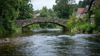 Fototapeta premium A bridge spans a river with a house in the background. The bridge is made of stone and the water is calm