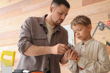 Father and his little son with different instruments assembling furniture in workshop