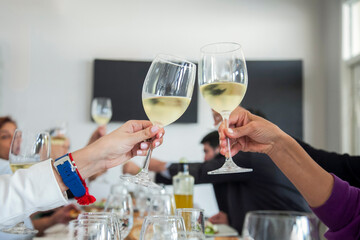 Friends Raising white Wine Glasses in Toast at Dining Table