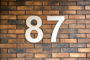 Number 87. Address sign on the brick wall.