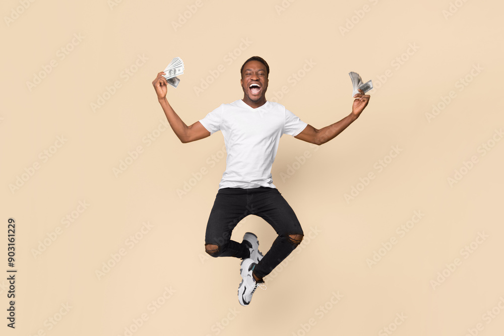 Poster Excited African American Guy Jumping Holding Bunch Of Money Celebrating Profit And Success Over Yellow Studio Background. Big Luck Concept