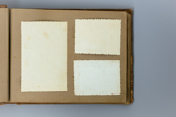 Clear blank photo frames to placed your pictures or text on old family album on grey background in retro style. Family traditions, memories and nostalgia concept. Antique album with old photos.