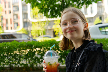 The image shows a girl holding a colorful fruit drink with a straw, she is smiling