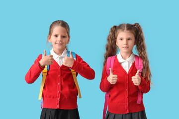 Little schoolgirls with backpacks on blue background