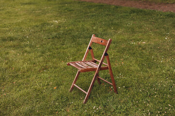 Empty wooden chair on the green lawn. Theme of loneliness.