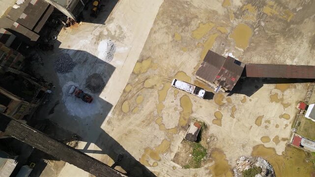 Aerial footage of halite or rock salt being loaded by a wheel front loader on a bulk cargo tipper truck. Drone shot of salt being poured in an industrial truck and weighed at a salt mine. Industrial
