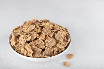 Whole grain corn flakes in a white bowl on a white background. Fitness breakfast. Top view.