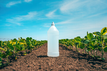 Herbicide bottle in perfectly clean soybean plantation field after herbicidal treatment of the crops and land