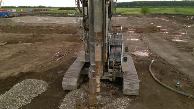 Aerial shot of shale gas drilling rig in a rural field in Romania. Fracking drill seen from above in the middle of a crop field. Drone footage of Hydraulic fracturing construction site.
