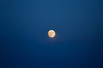 A large full moon shines brightly in the night sky.