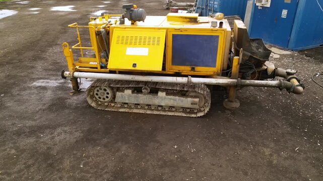 Aerial view of a compact tracked industrial machine operating beside a portable power unit and temporary site cabin, showing heavy-duty equipment used for construction, drilling or ground engineering 