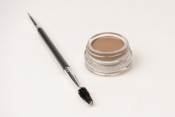 A brow pomade in blonde shade with brush isolated on a white background.