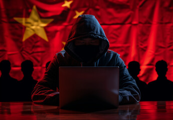 Anonymous identity hacker wearing hoodie using computer typing with chinese flag background cyber...