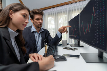 Two business traders consulting dynamic stock market in currency rate investment trading on two...