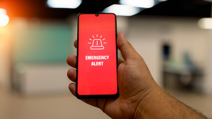 “EMERGENCY” warning message on mobile smartphone screen. Weather event alert, phone security...