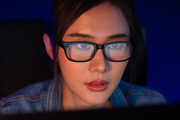 Portrait young beautiful Asian creative with glasses of serious face looking on pc to search project creator social media online, planning strategy creator at neon modern office at night. Stratagem.