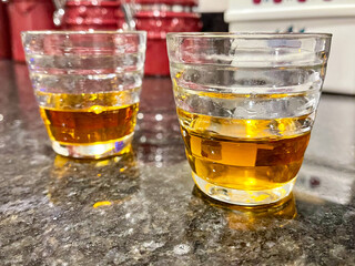 Shot glasses on a kitchen counter filled with an amber colored whiskey