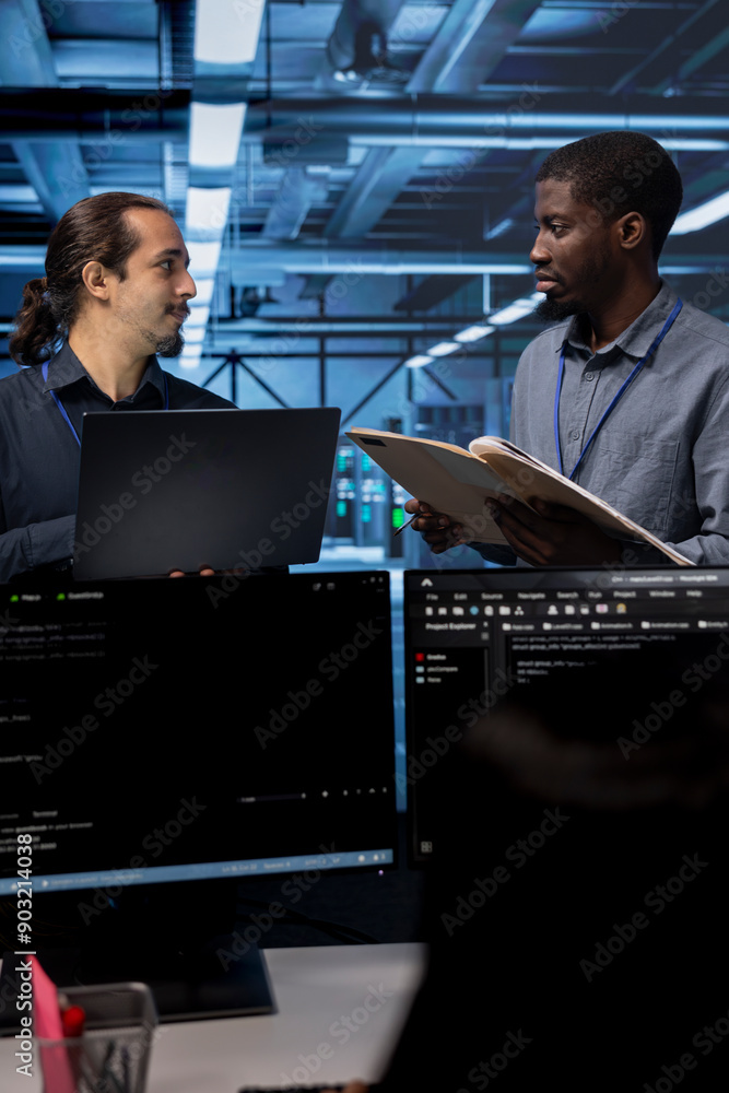 Poster manager getting feedback from engineer while overseeing data center, looking for firewall misconfigu