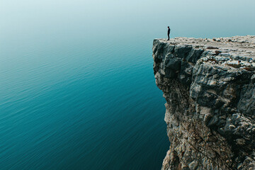 Photograph of a Diver on the Edge of a Cliff: A person standing at the edge of a cliff, ready to dive into the water below.
