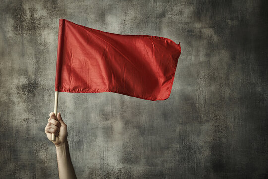 Photograph of a Hand Holding a Red Flag: A hand raising a red flag, symbolizing warning or risk.