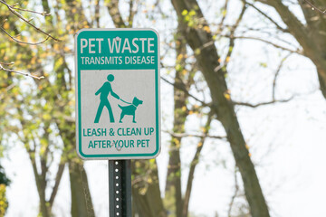 metal road sign that reads Pet Waste Transmits Disease, Leash and Clean Up After Your Pet, seen...