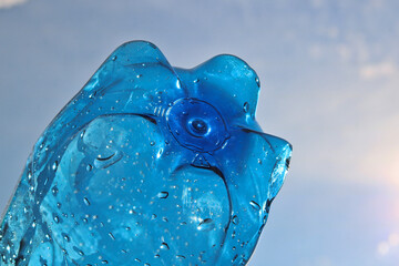Close-up of the bottom of a mineral water bottle in the backlight of the sky