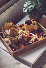 Wooden tray with breakfast and a garland on the bedside table.