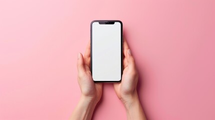 A closeup of hands holding a smartphone with a blank screen set against a vibrant pink background
