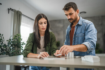 couple boyfriend and girlfriend play dominoes at home and have fun