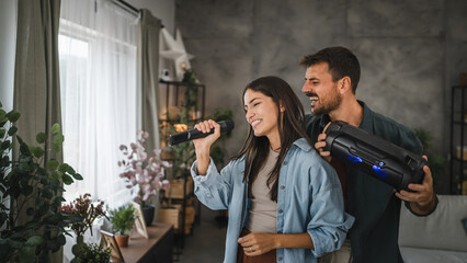 Couple have karaoke party at home sing on mic, dance with loudspeaker