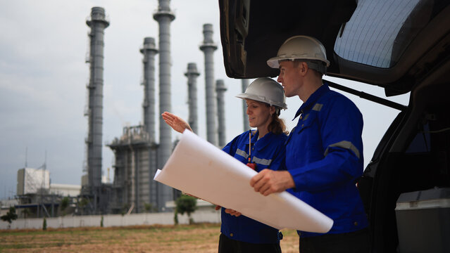 Engineer couple male  and female working with blueprint and discussion at the trunk of the car in power plant industrial 