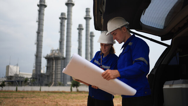 Engineer couple male  and female working with blueprint and discussion at the trunk of the car in power plant industrial 
