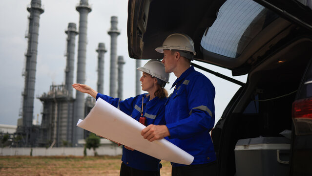 Engineer couple male  and female working with blueprint and discussion at the trunk of the car in power plant industrial 