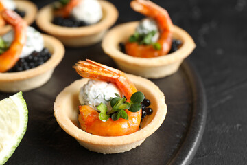 Delicious canapes with shrimps and black caviar on table, closeup