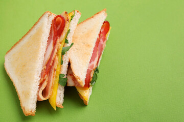Delicious sandwiches with bacon on green background, above view. Space for text