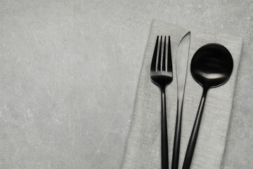 Stylish cutlery and napkin on grey table, top view. Space for text
