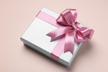 Beautiful gift box with pink bow on beige background