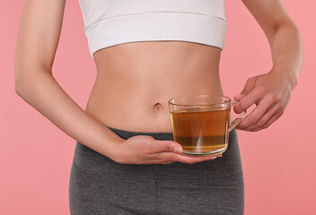 Weight loss concept. Woman with cup of diet tea on pink background, closeup