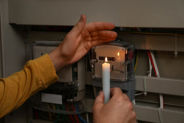 Man with candle checking electricity meter indoors, closeup