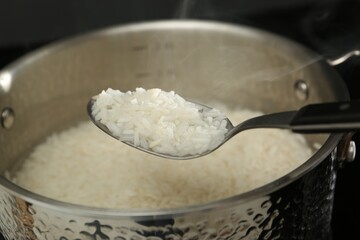 Taking boiled rice from pot with spoon, closeup