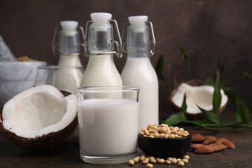 Different types of vegan milk and ingredients on wooden table