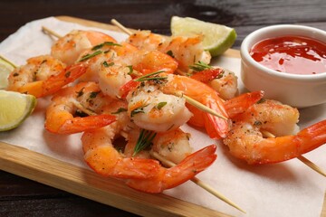 Skewers with delicious grilled shrimps served on wooden table, closeup