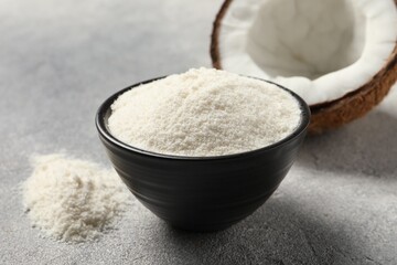 Coconut flour in bowl and fresh fruit on light grey table, closeup