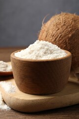 Organic coconut flour in bowl and fresh fruit on wooden table, closeup