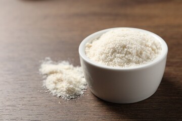 Organic coconut flour in bowl on wooden table, closeup