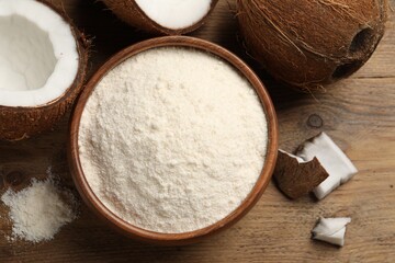 Organic coconut flour in bowl and fresh fruits on wooden table, flat lay