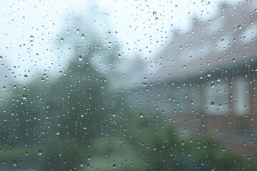 View on buildings through window with water droplets on rainy day, closeup
