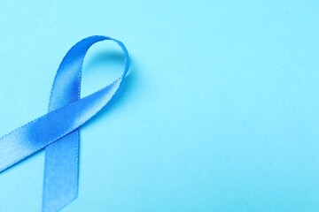 Prostate cancer awareness. Blue ribbon on color background, closeup. Space for text