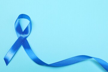 Blue ribbon on color background, top view with space for text. Prostate cancer awareness